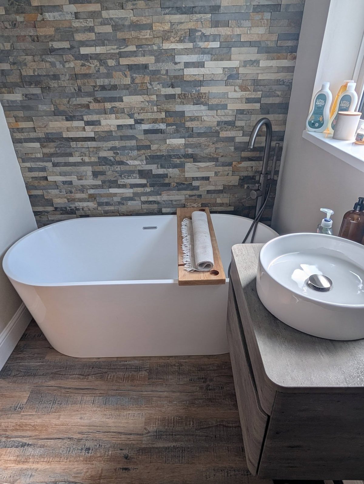 A freestanding bath and stone-tiled bathroom cleaned to a shine